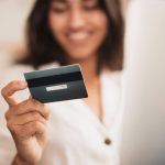 Mulher sorrindo segurando cartão de crédito