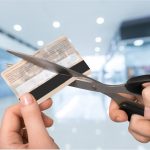 Mulher com tesoura cortando um cartão de crédito para cancelar